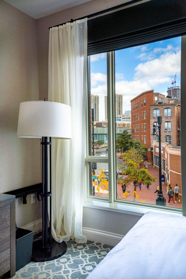 Looking out the window from a room at The Whitney Hotel Boston, with a view of the brick buildings and pedestrians on Charles Street below.