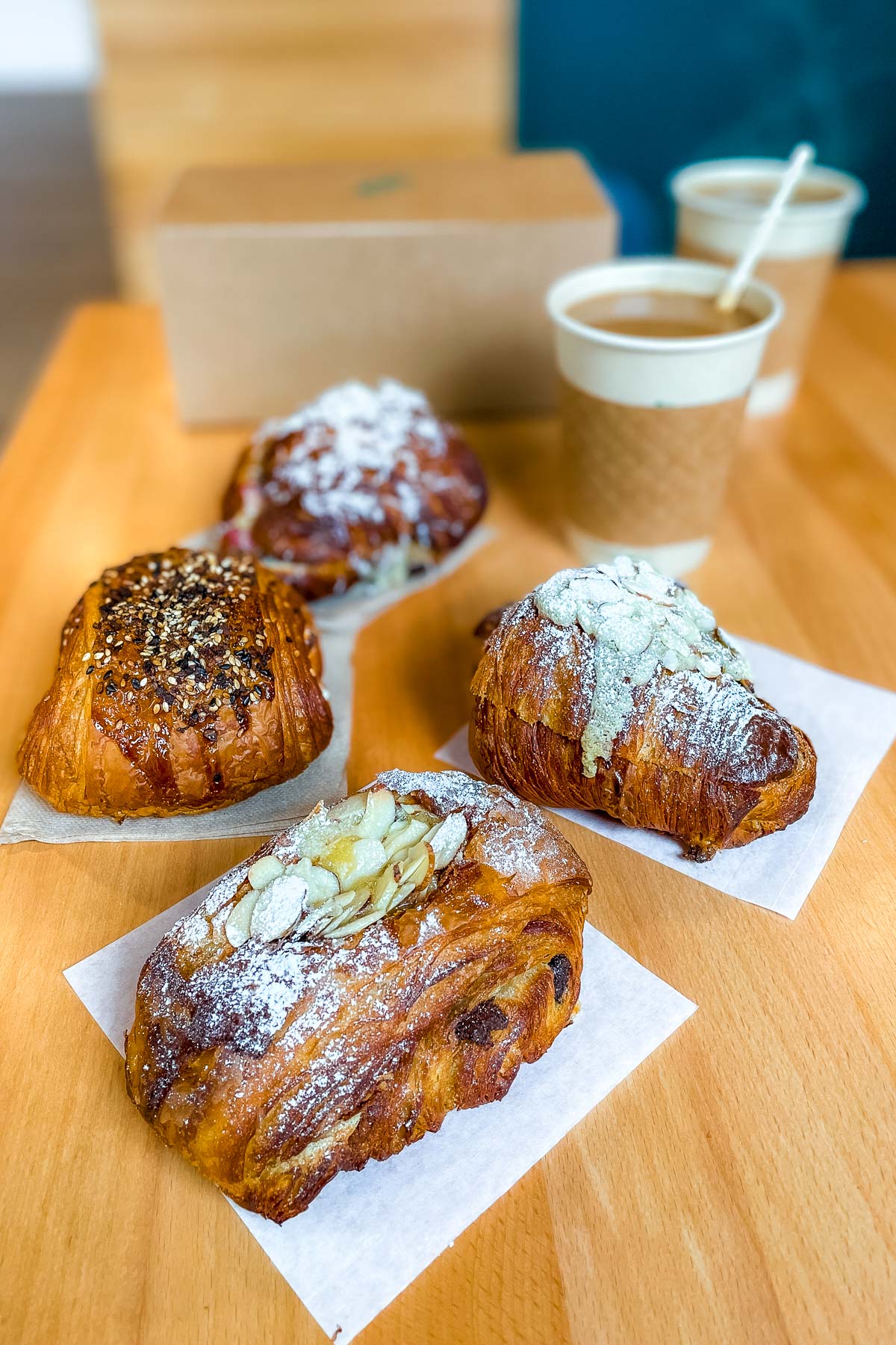 A close-up of fresh pastries topped with powdered sugar and almonds, served with coffee at Woodland Baking and Coffee in Stowe, Vermont.